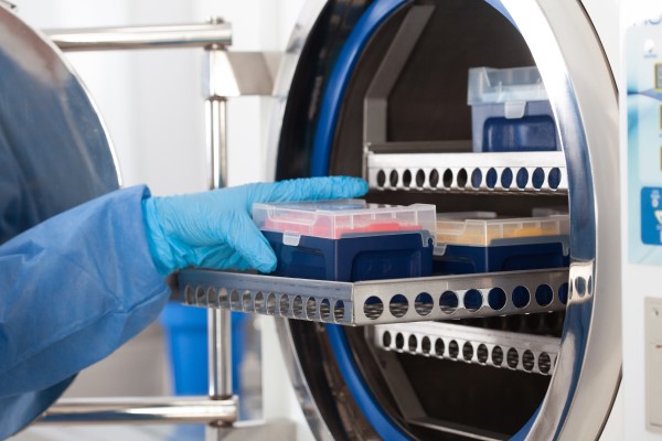 Cientista esterilizando material de laboratório na autoclave.