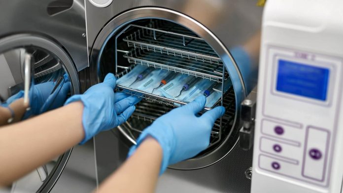Cientista retira instrumentos de autoclave para laboratório horizontal.