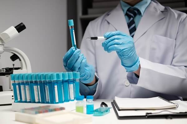 Cientista identificando amostras em tubos de ensaio com tampa no laboratório.