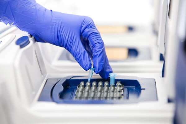 Cientista inserindo tubos em sequenciador de DNA.